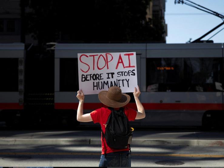 A protester holds a sign during a protest outside of OpenAI headquarters