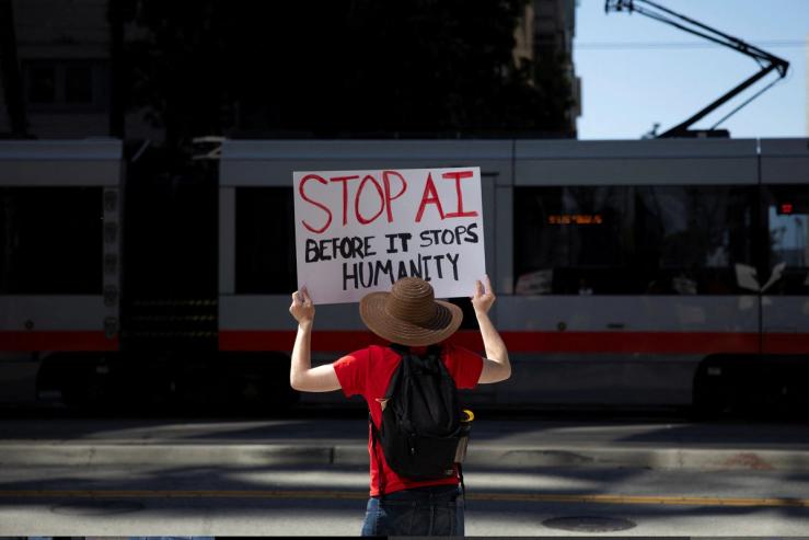 A protester holds a sign during a protest outside of OpenAI headquarters