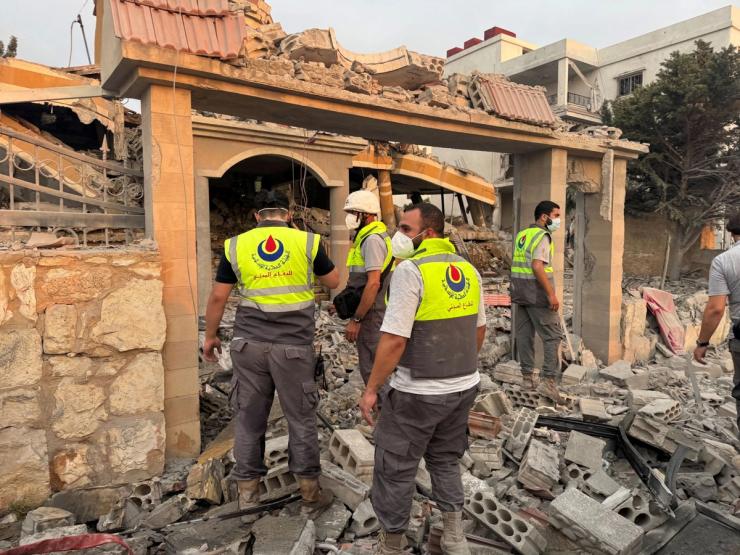 Members of civil defence stand on rubble at a damaged site after Israeli strikes in southern Lebanon.