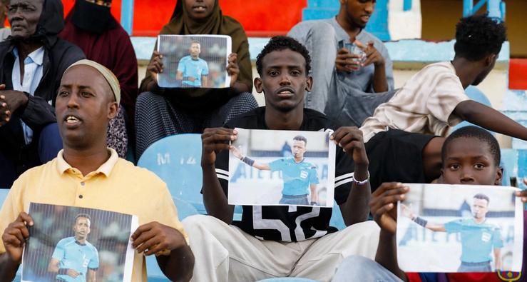 Somalis hold pictures of referee Omar Abdulkadir Artan, who had been expected to officiate matches at the 2026 FIFA World Cup but was refused entry to the United States, during a match between Gaadiidka and Juba at Mogadishu Stadium, in Mogadishu, Somalia, June 9, 2026.