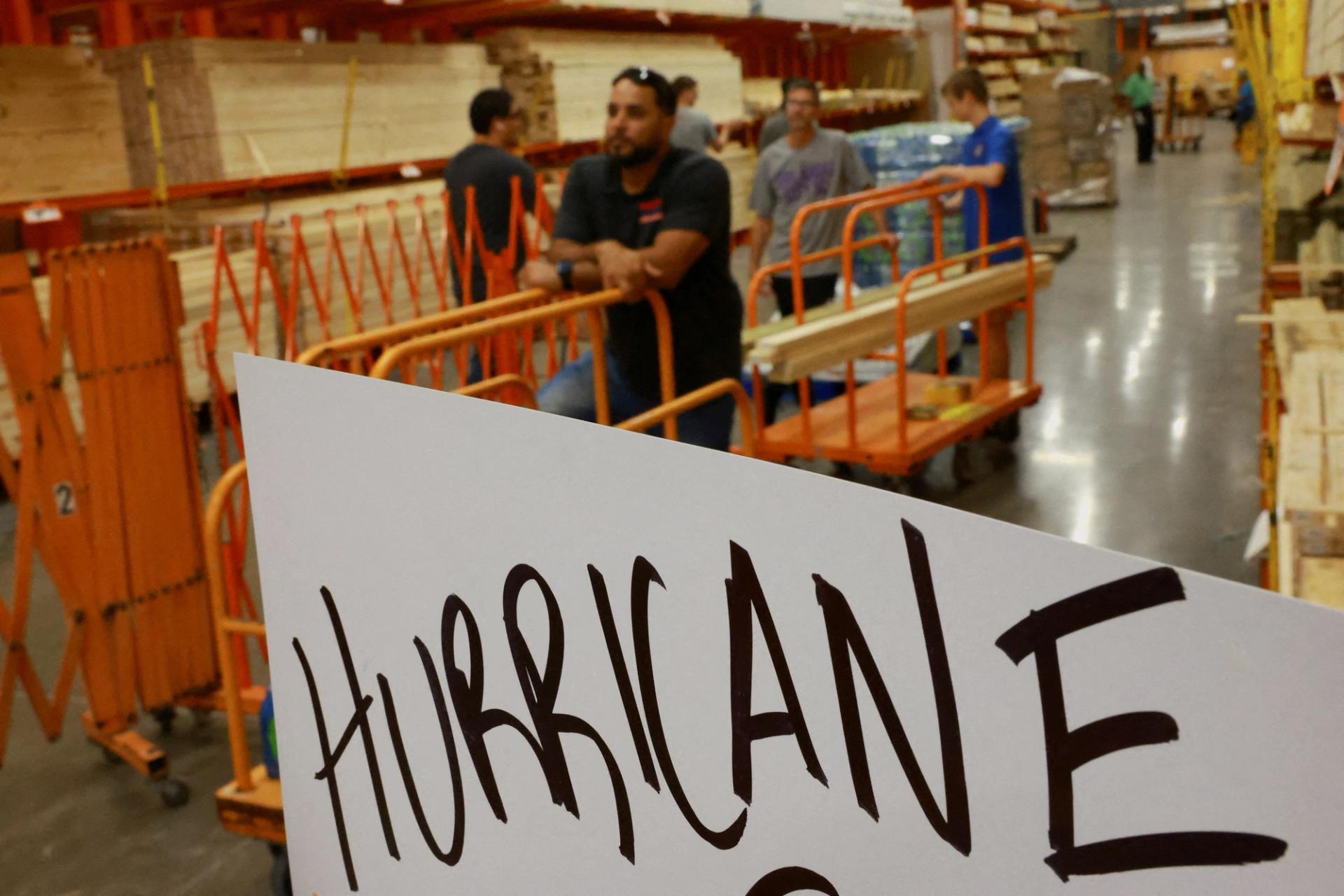 People line up to buy wood in Orlando. A sign reads "Hurricane" 