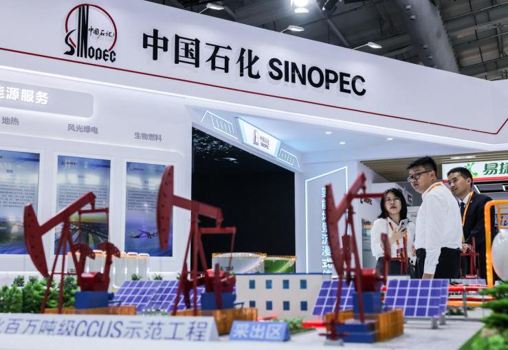 People look on with models of oil pump jacks seen in the foreground at China Petroleum & Chemical Corporation, or Sinopec, booth at China International Fair for Trade in Services (CIFTIS) in Beijing