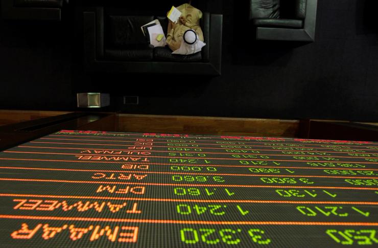 A stock exchange information is seen on a screen is seen as a man works on the trading floor at the Dubai Financial Market