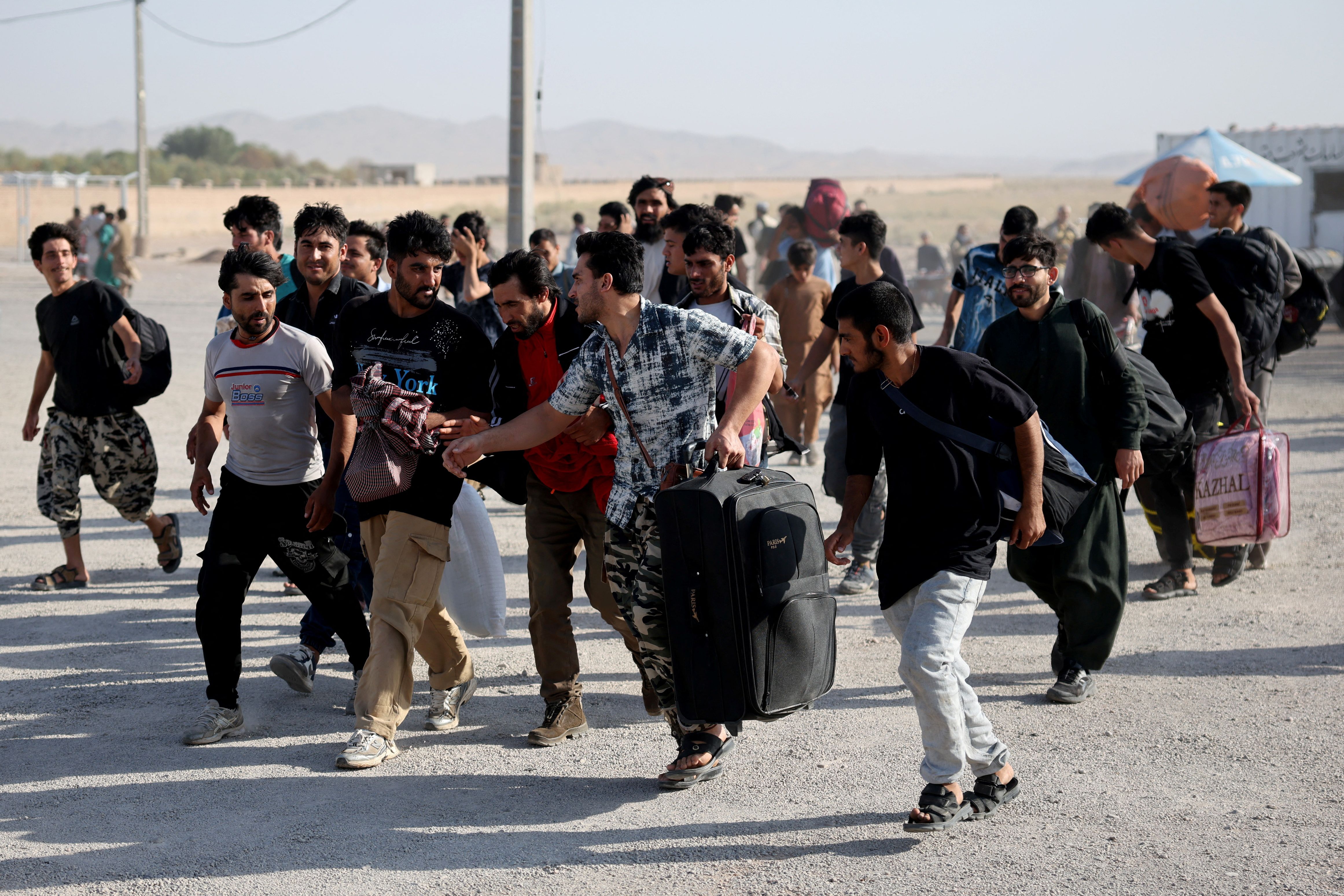 Afghan nationals carrying their belongings walk after crossing the border from Iran 