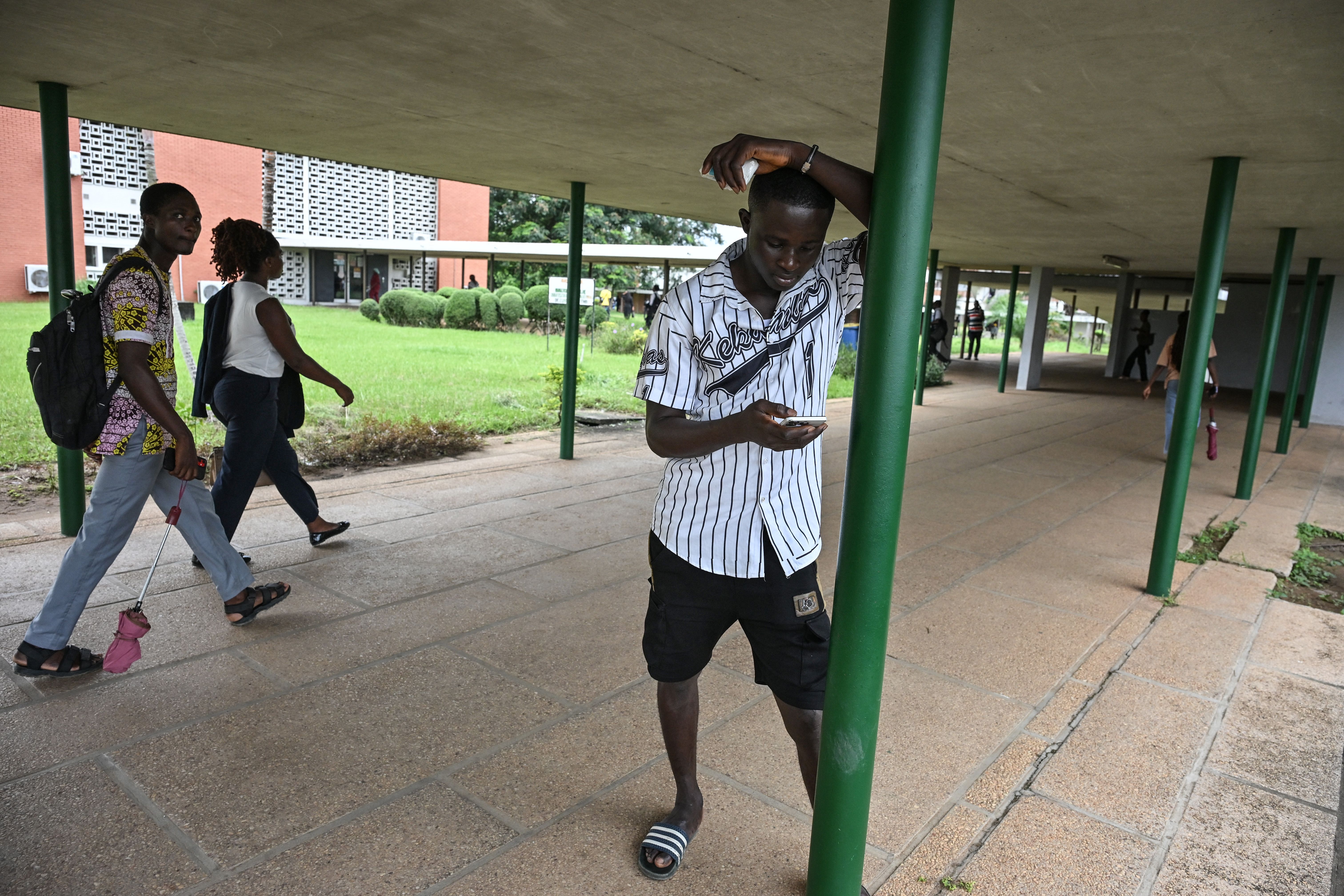Erman Kouassi Konan looks at his phone at Felix Houphouet-Boigny University in Abidjan. 