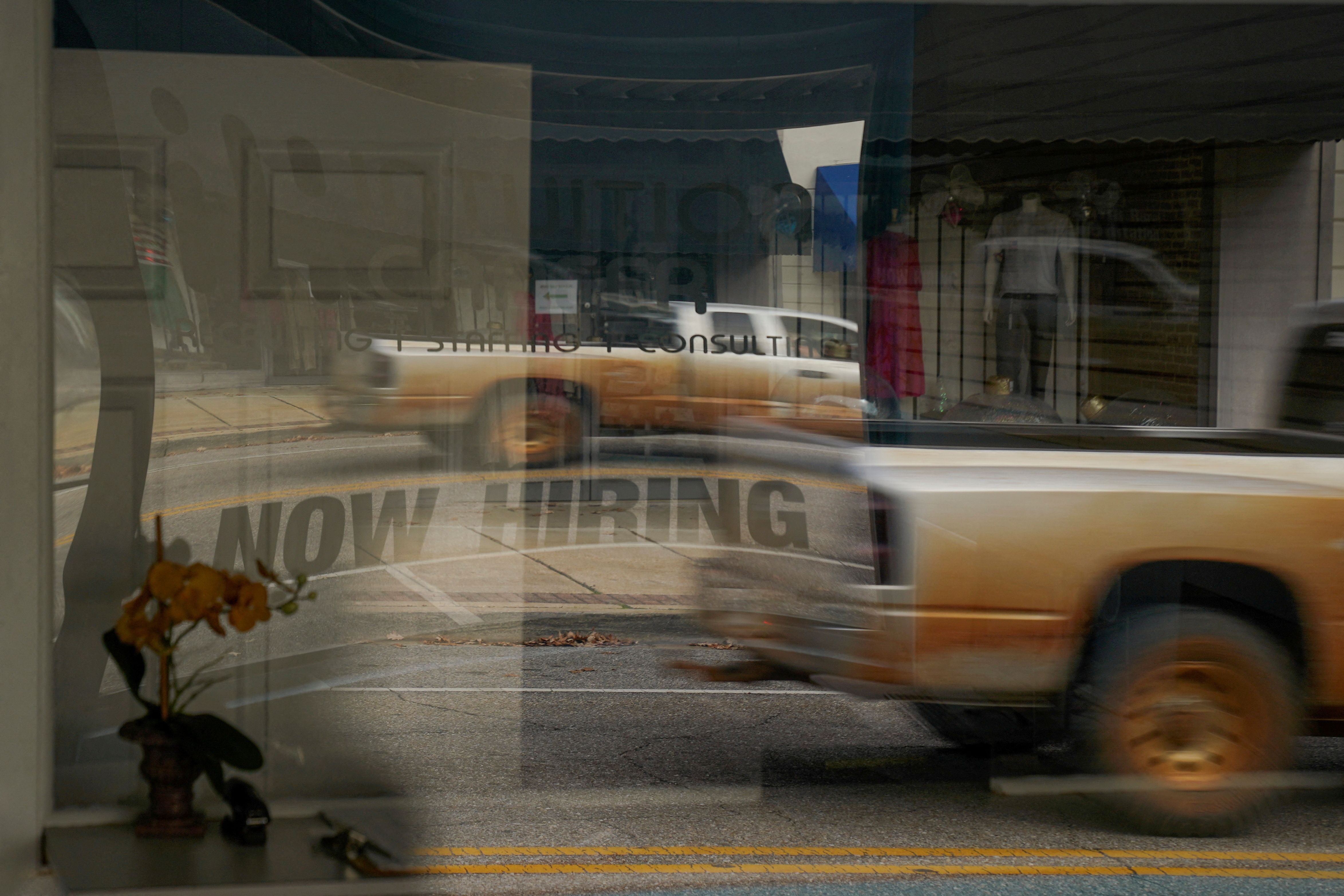 A “Now Hiring” sign is reflected through the window of Intuition Career staffing agency in Greenville, Alabama, U.S., December 4, 2022. 