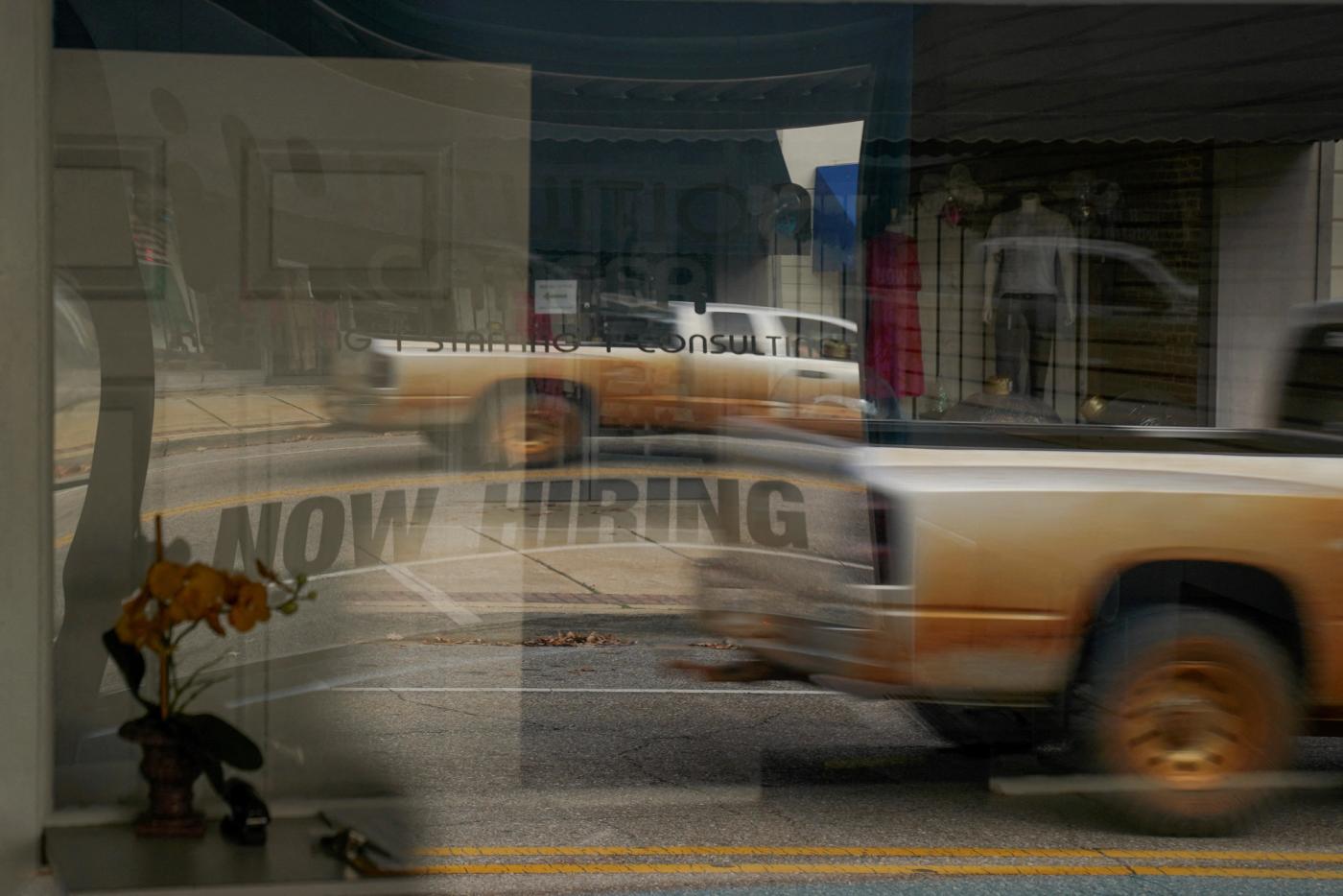 A "Now Hiring" sign is reflected through the window of Intuition Career staffing agency in Greenville, Alabama, U.S., December 4, 2022. 