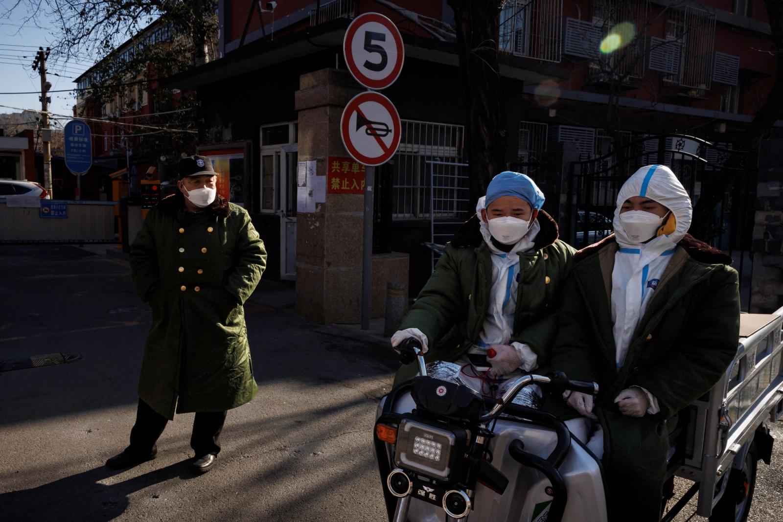 Pandemic prevention workers in protective suits ride an electric vehicle as coronavirus disease (COVID-19) outbreaks continue in Beijing