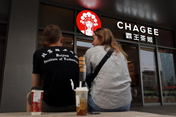 People sit outside a store of Chinese tea chain Chagee at a shopping mall in Beijing