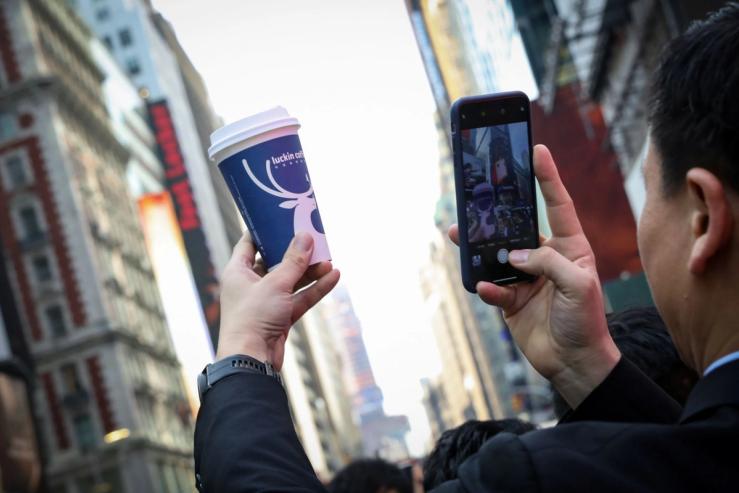 A man photographs his cup of Luckin coffee.