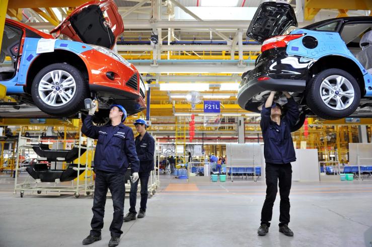 Employees install car components at an assembly line at a Ford manufacturing plant in Chongqing municipality.