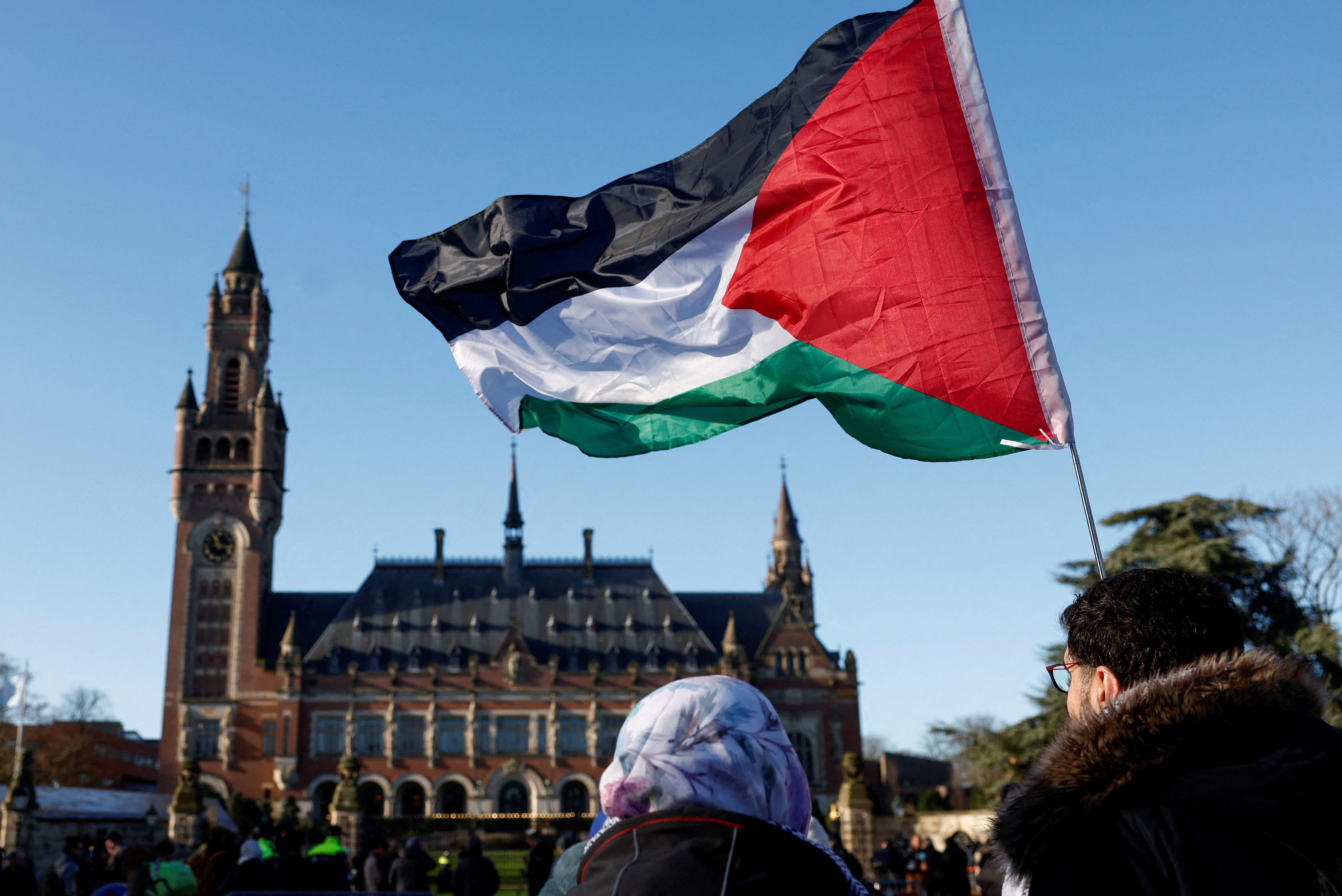 FILE PHOTO: Protesters hold a Palestinian flag as they gather outside the International Court of Justice (ICJ) as judges rule on emergency measures against Israel following accusations by South Africa that the Israeli military operation in Gaza is a state-led genocide, in The Hague, Netherlands, January 26, 2024. REUTERS/Piroschka van de Wouw/File Photo