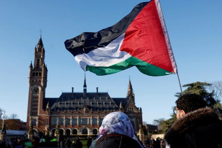 FILE PHOTO: Protesters hold a Palestinian flag as they gather outside the International Court of Justice (ICJ) as judges rule on emergency measures against Israel following accusations by South Africa that the Israeli military operation in Gaza is a state-led genocide, in The Hague, Netherlands, January 26, 2024. REUTERS/Piroschka van de Wouw/File Photo