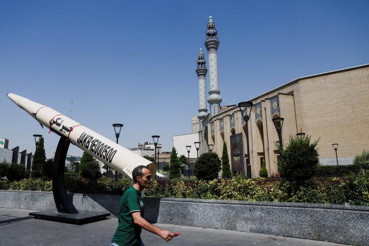 A man walks next to a symbolic mock-up of an Iranian missile, on a street in Tehran.