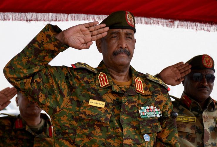 Sudanese General Abdel Fattah al-Burhan salutes as he listens to the national anthem