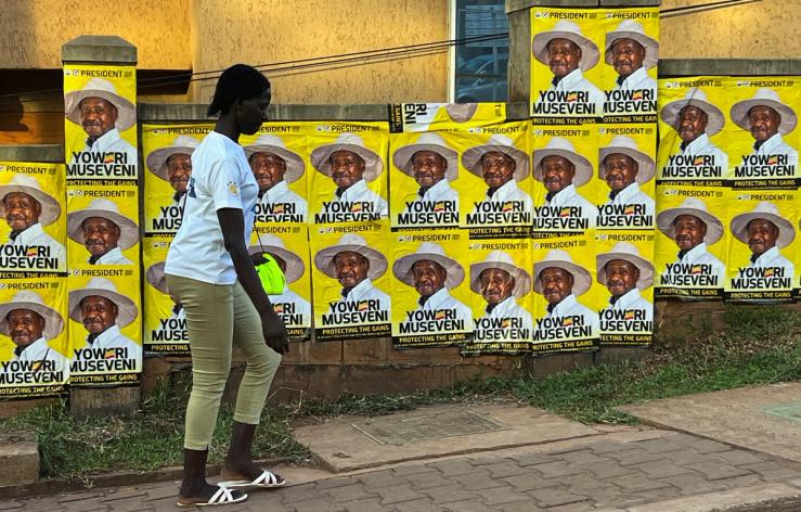 A woman walks past campaign posters of Yoweri Museveni.