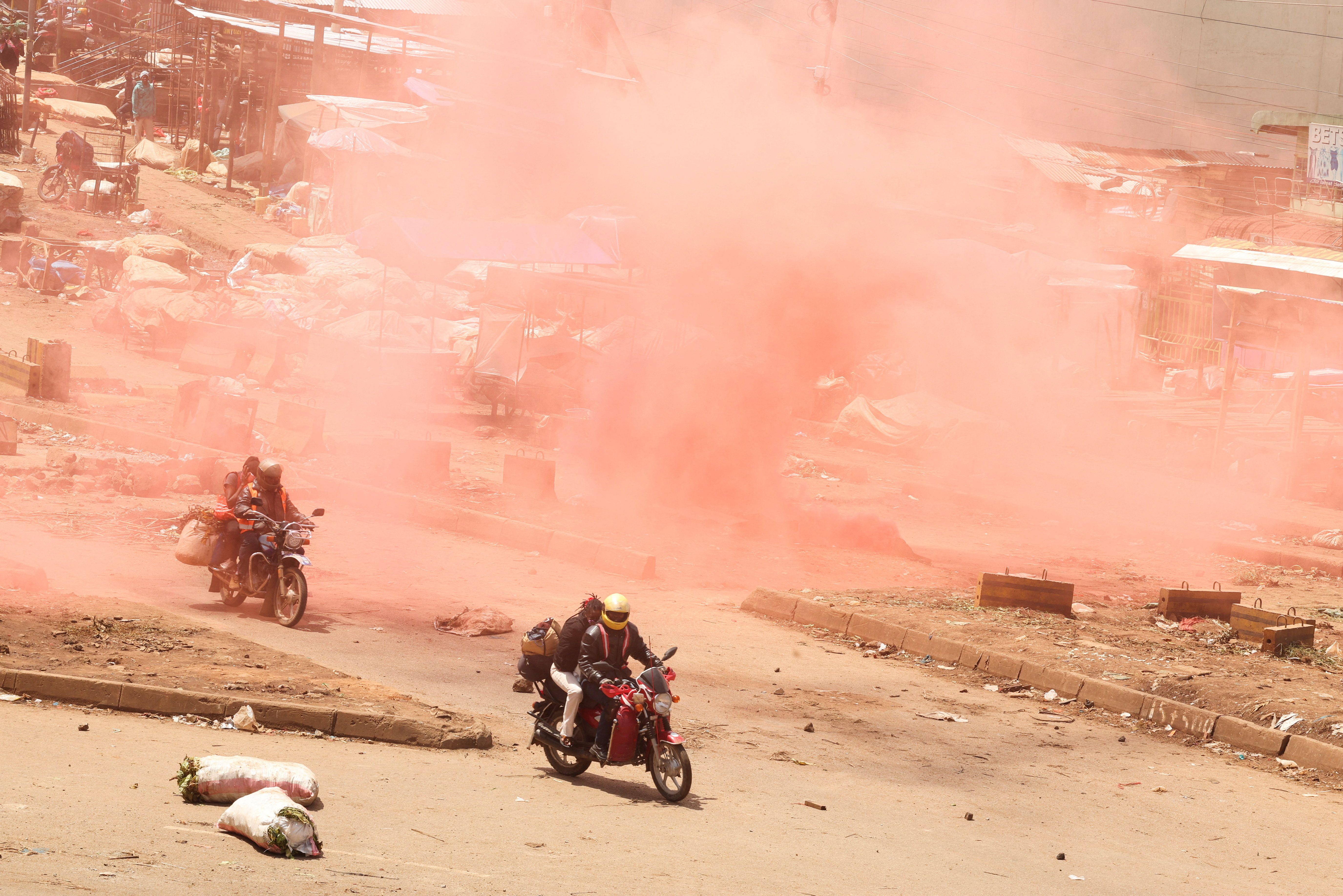 Motorcycle taxis ride through colored tear gas during protests in Nairobi.