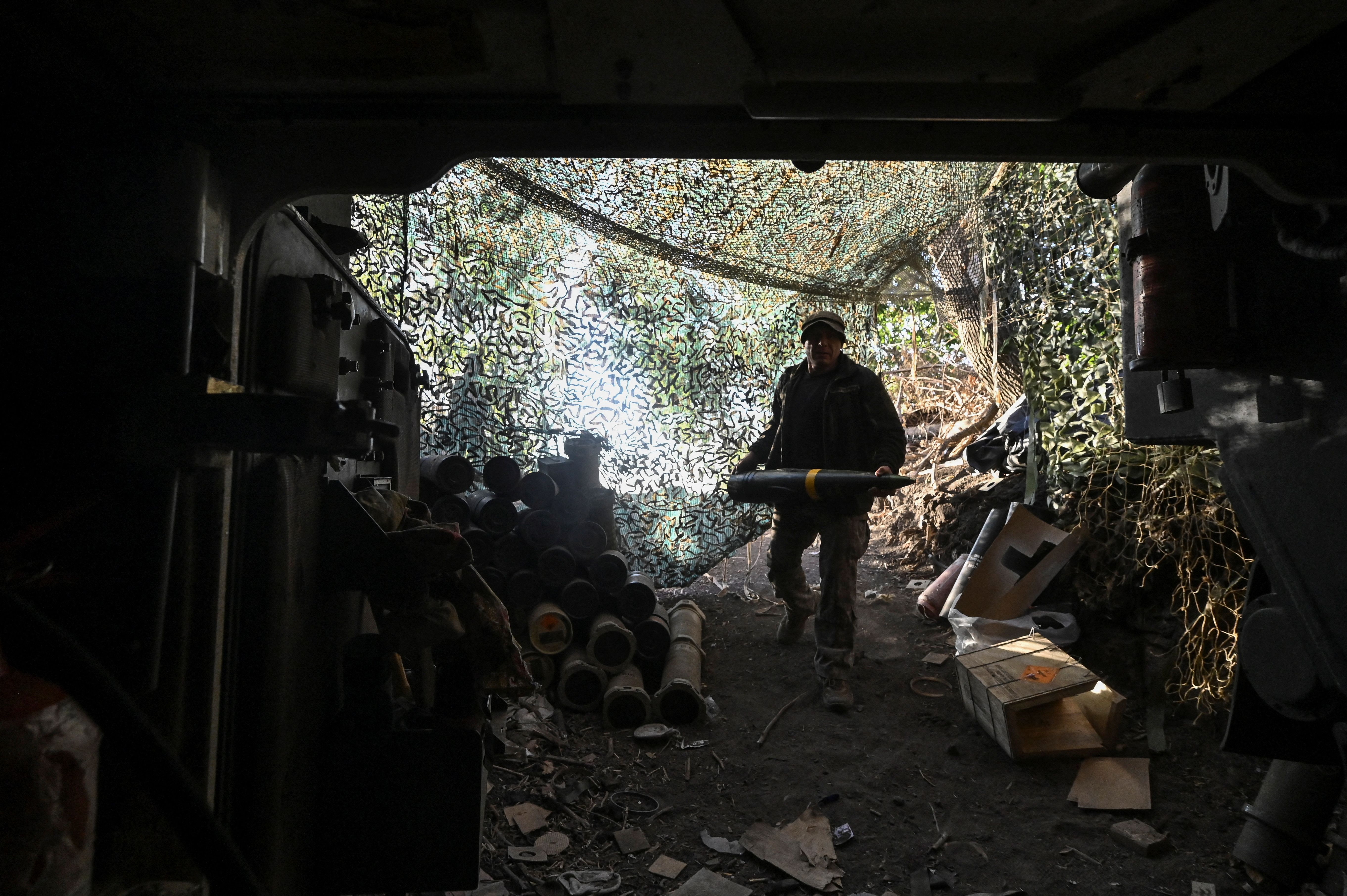 A Ukrainian serviceman carries a 155 mm shell.