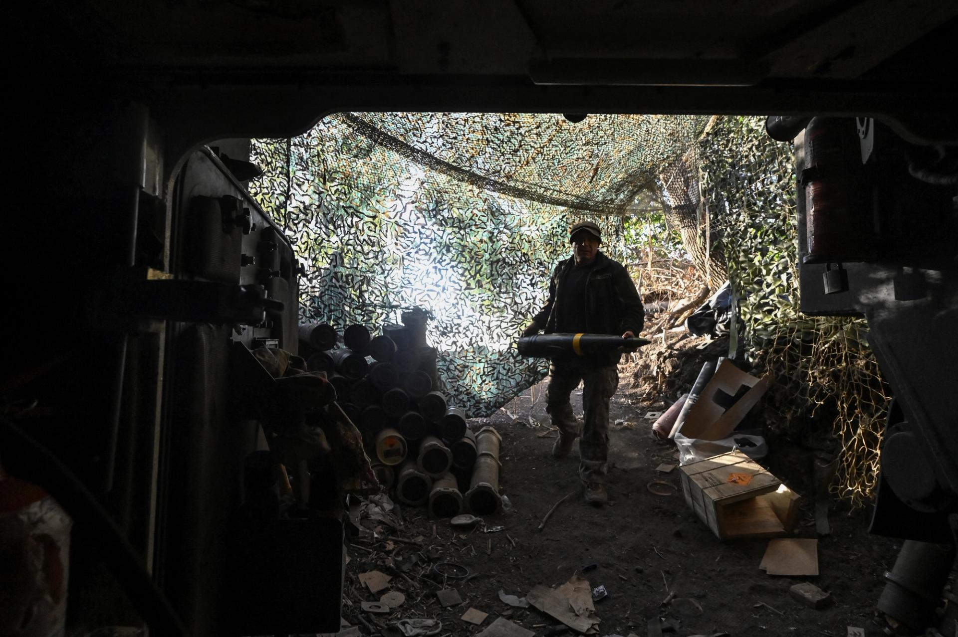 A Ukrainian serviceman carries a 155 mm shell.