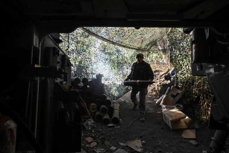 A Ukrainian serviceman carries a 155 mm shell.