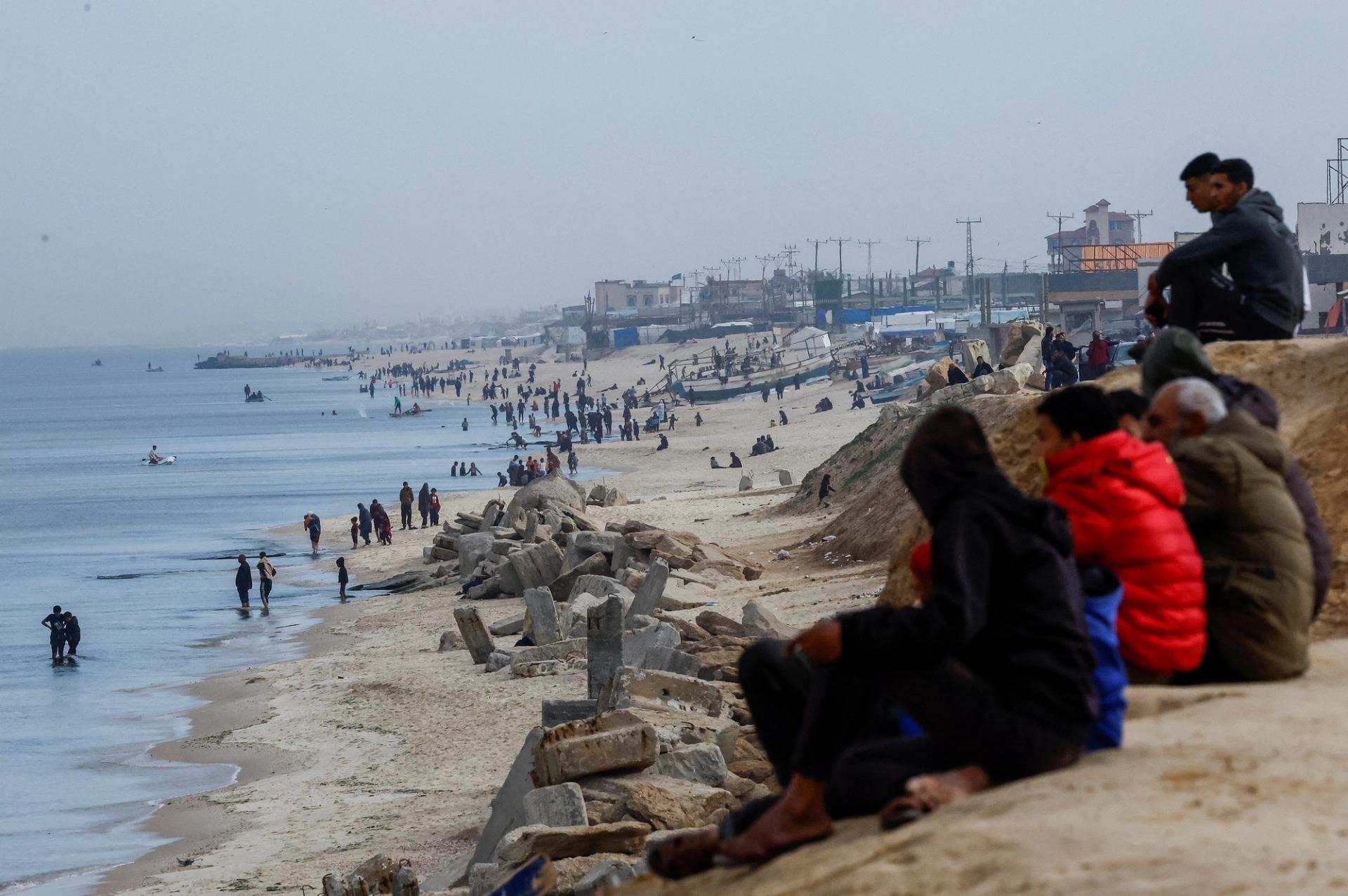 Palestinians sit near Mediterranean Sea, amid the ongoing conflict between Israel and Palestinian Islamist group Hamas, in Rafah, in the southern Gaza Strip, February 13, 2024. REUTERS/Mohammed Salem