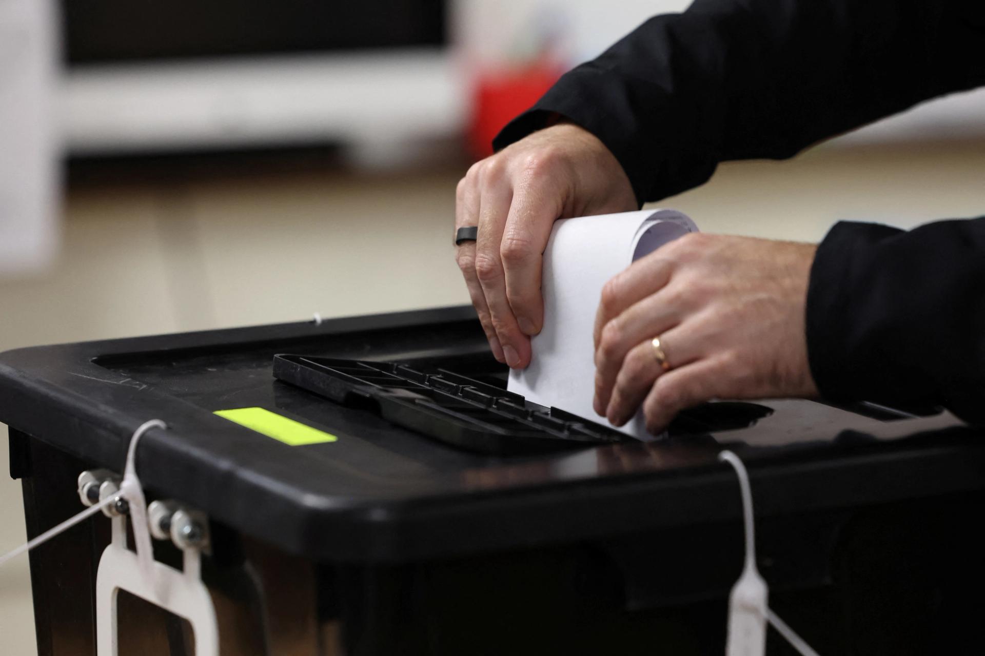 Person casting a vote in a ballot box.