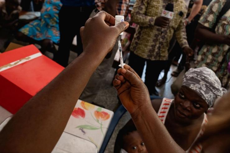 A nurse holds a syringe as patients wait in Ghana on April 23, 2019.