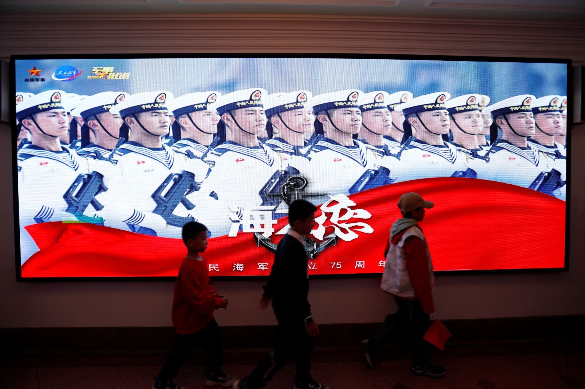Children walk past a display marking the 75th founding anniversary of the Chinese People’s Liberation Army (PLA) Navy, during a media tour to an open day at the PLA Naval Submarine Academy, ahead of the Navy’s 75th founding anniversary, in Qingdao, Shandong province, China 