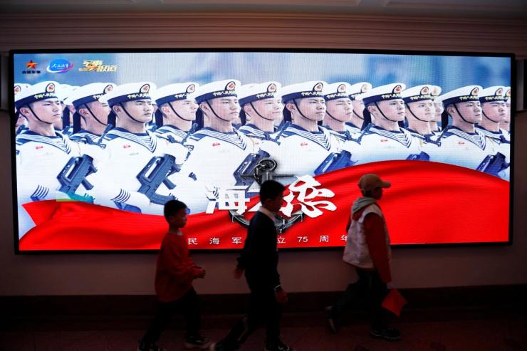 Children walk past a display marking the 75th founding anniversary of the Chinese People’s Liberation Army (PLA) Navy, during a media tour to an open day at the PLA Naval Submarine Academy, ahead of the Navy’s 75th founding anniversary, in Qingdao, Shandong province, China