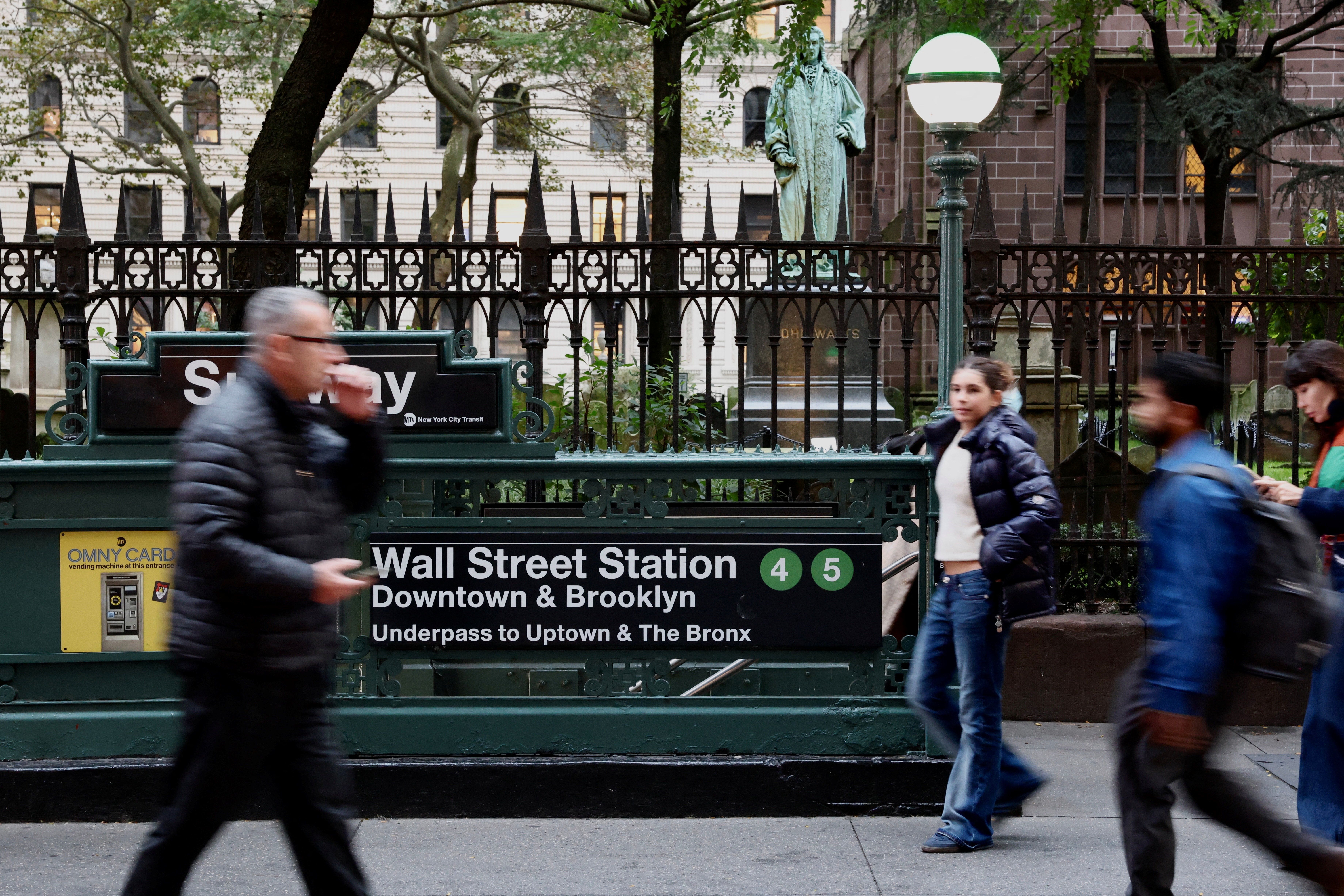 People pass by the subway station at Wall Street ahead of trading at the New York Stock Exchange
