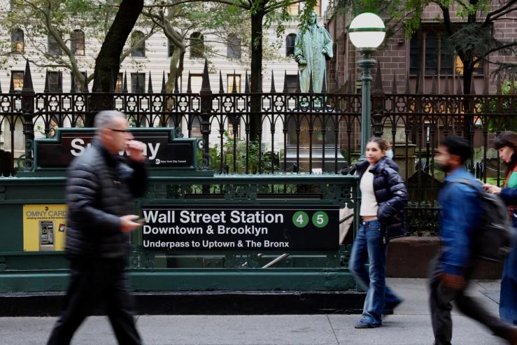 People pass by the subway station at Wall Street ahead of trading at the New York Stock Exchange