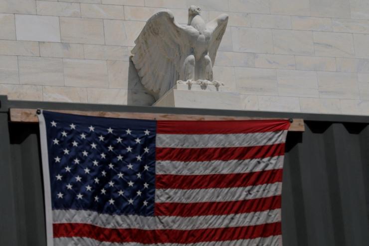 An eagle tops the US Federal Reserve building’s facade above a US flag hanging on a construction trailer.