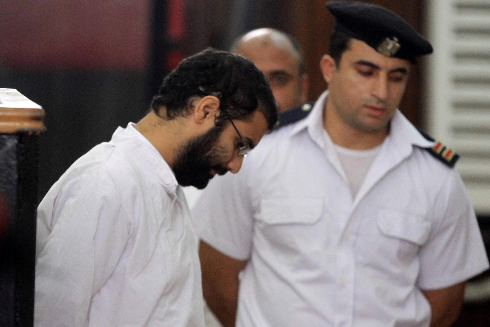 Activist Alaa Abd el-Fattah stands in front of a police officer at a court during his trial in Cairo.