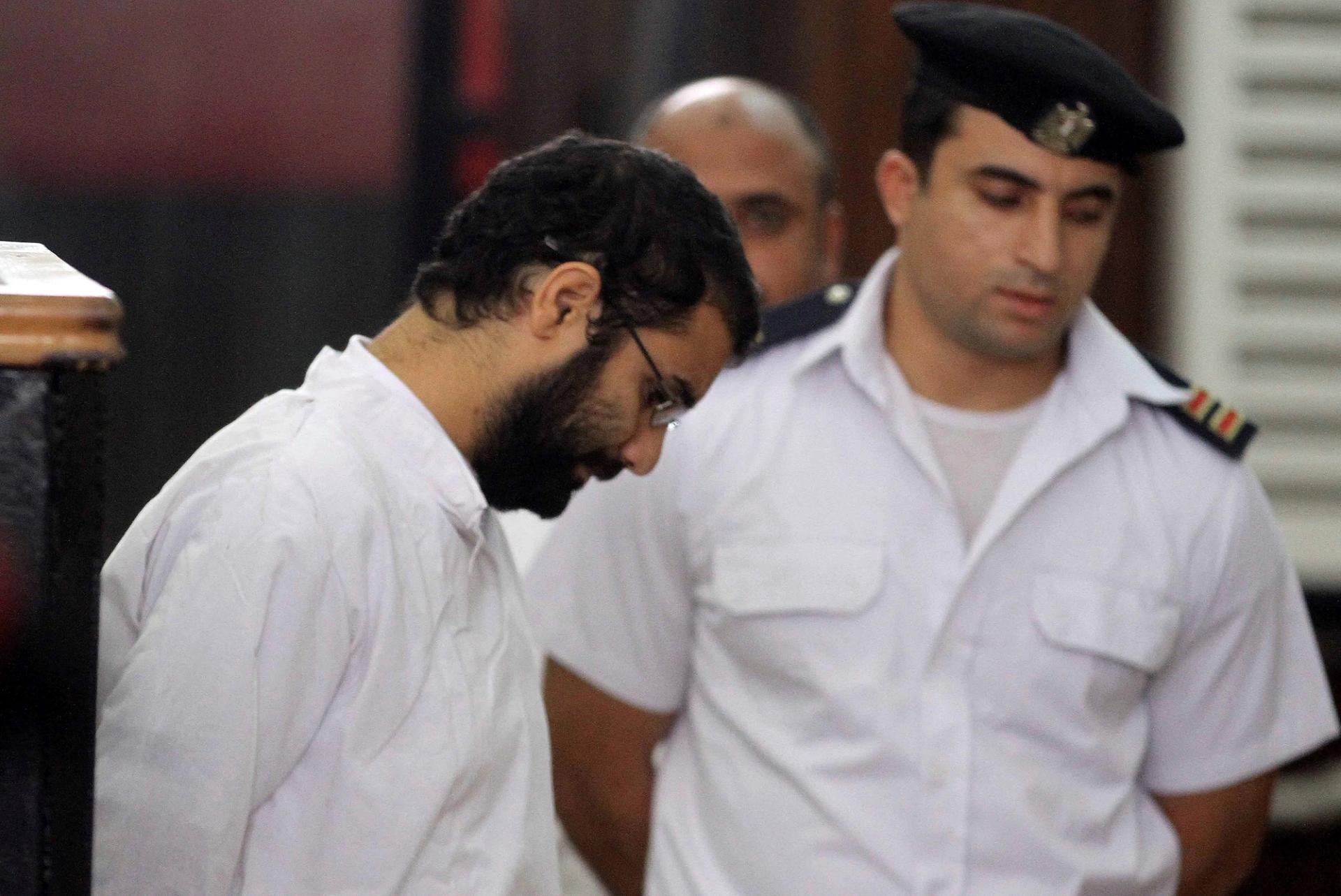 Activist Alaa Abd el-Fattah stands in front of a police officer at a court during his trial in Cairo.