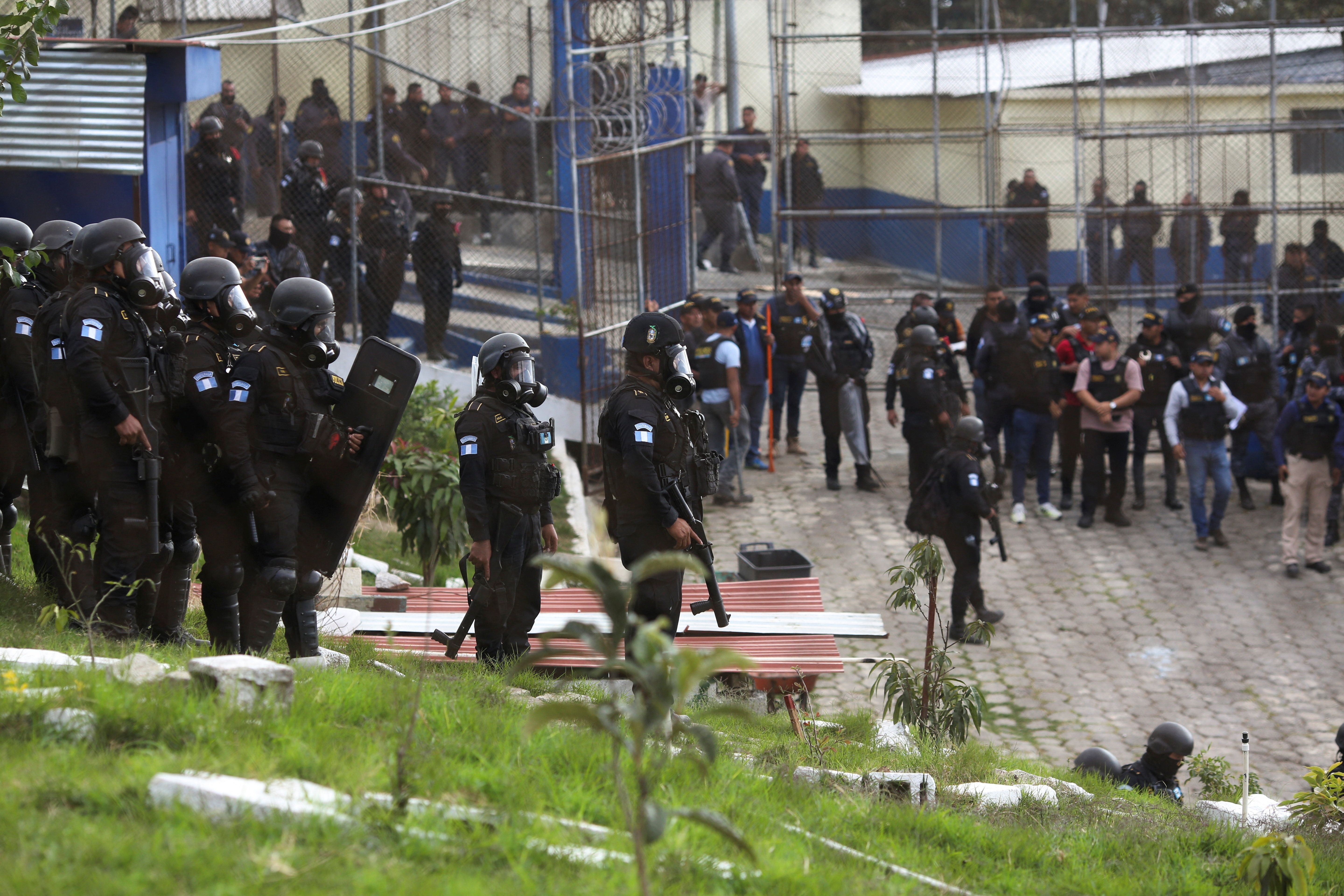 Riot police officers enter Zone 18 prison during gang violence following prison riots that left several police officers dead, in Guatemala City. 