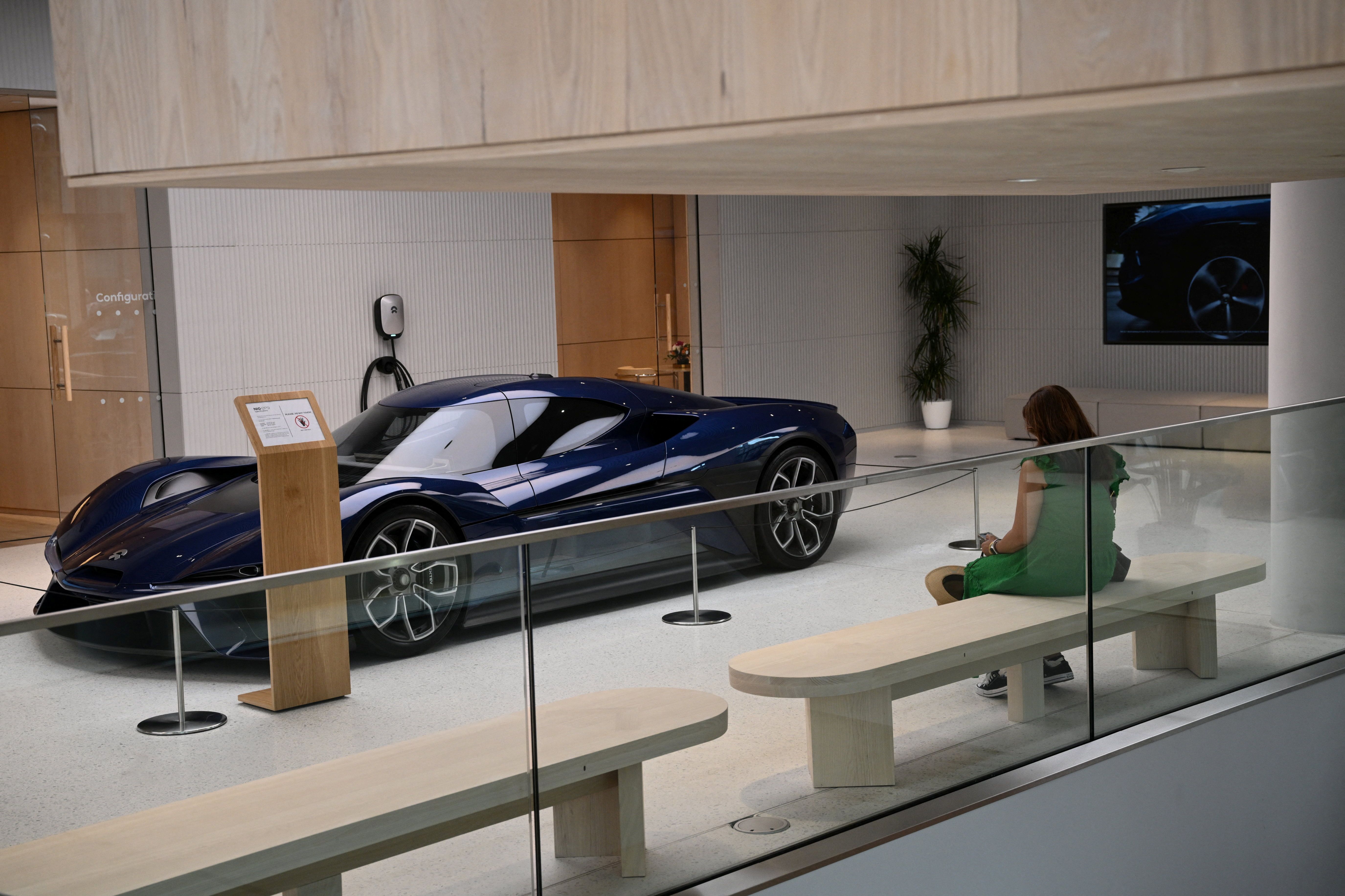 A woman sits near a sports car at the NIO House showroom in Berlin.