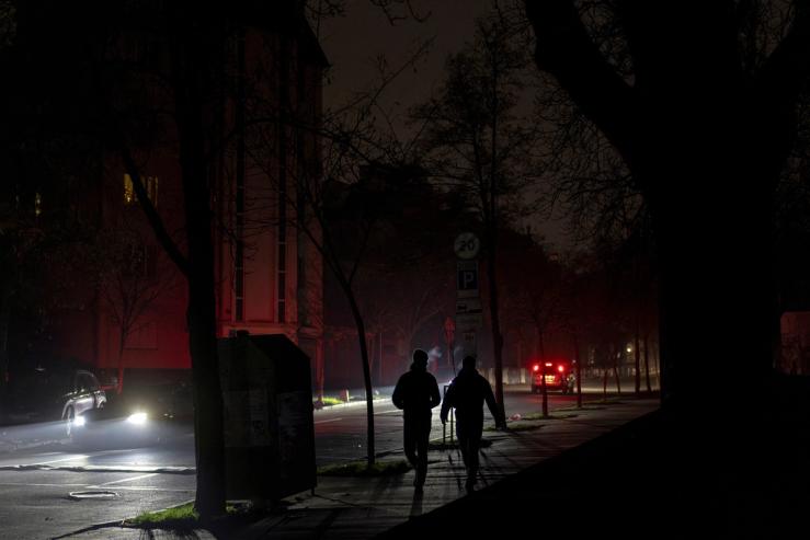 People walk in an unlit street in Kyiv.