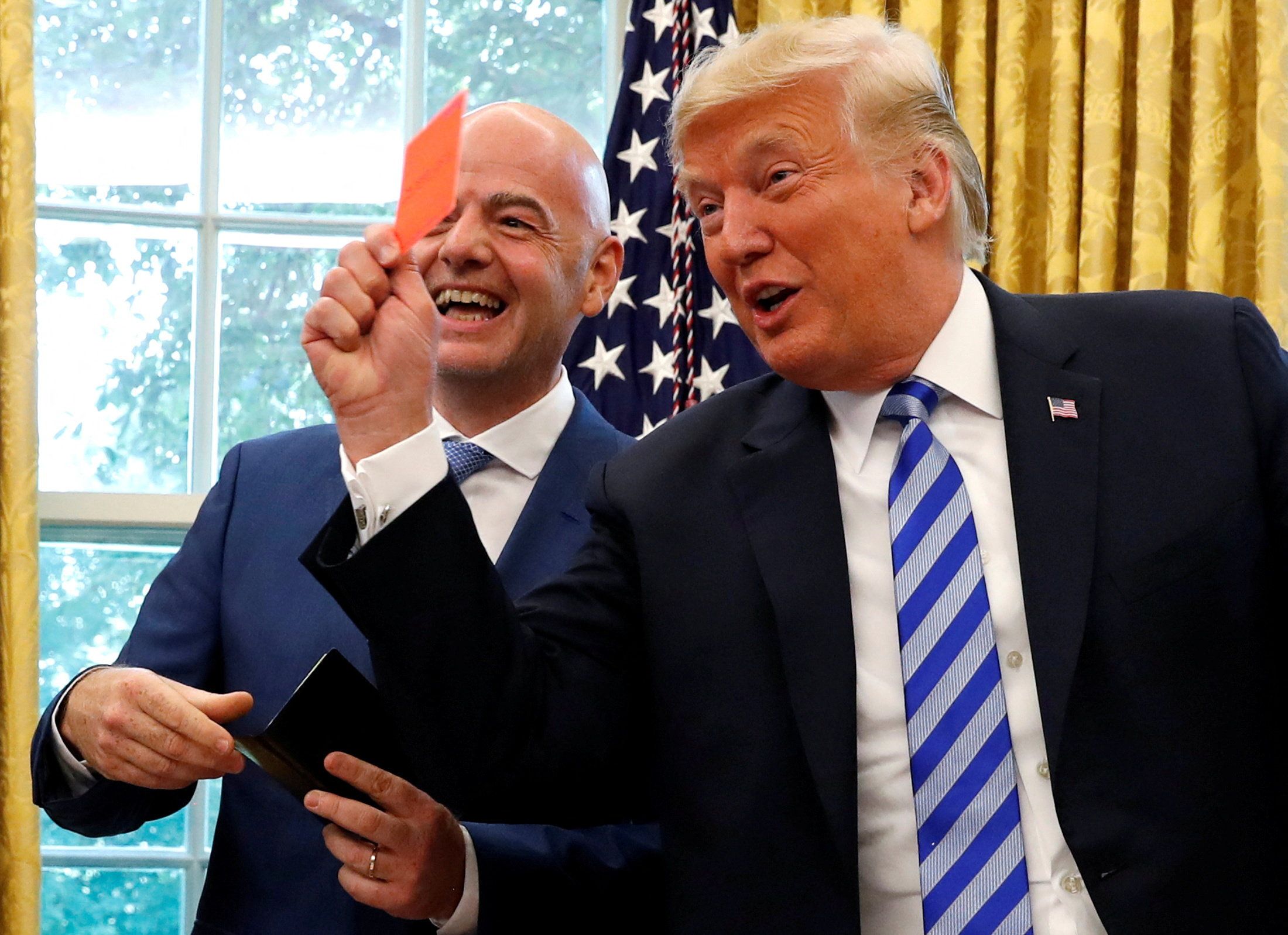 President Donald Trump holds up a red card as he meets with FIFA President Gianni Infantino