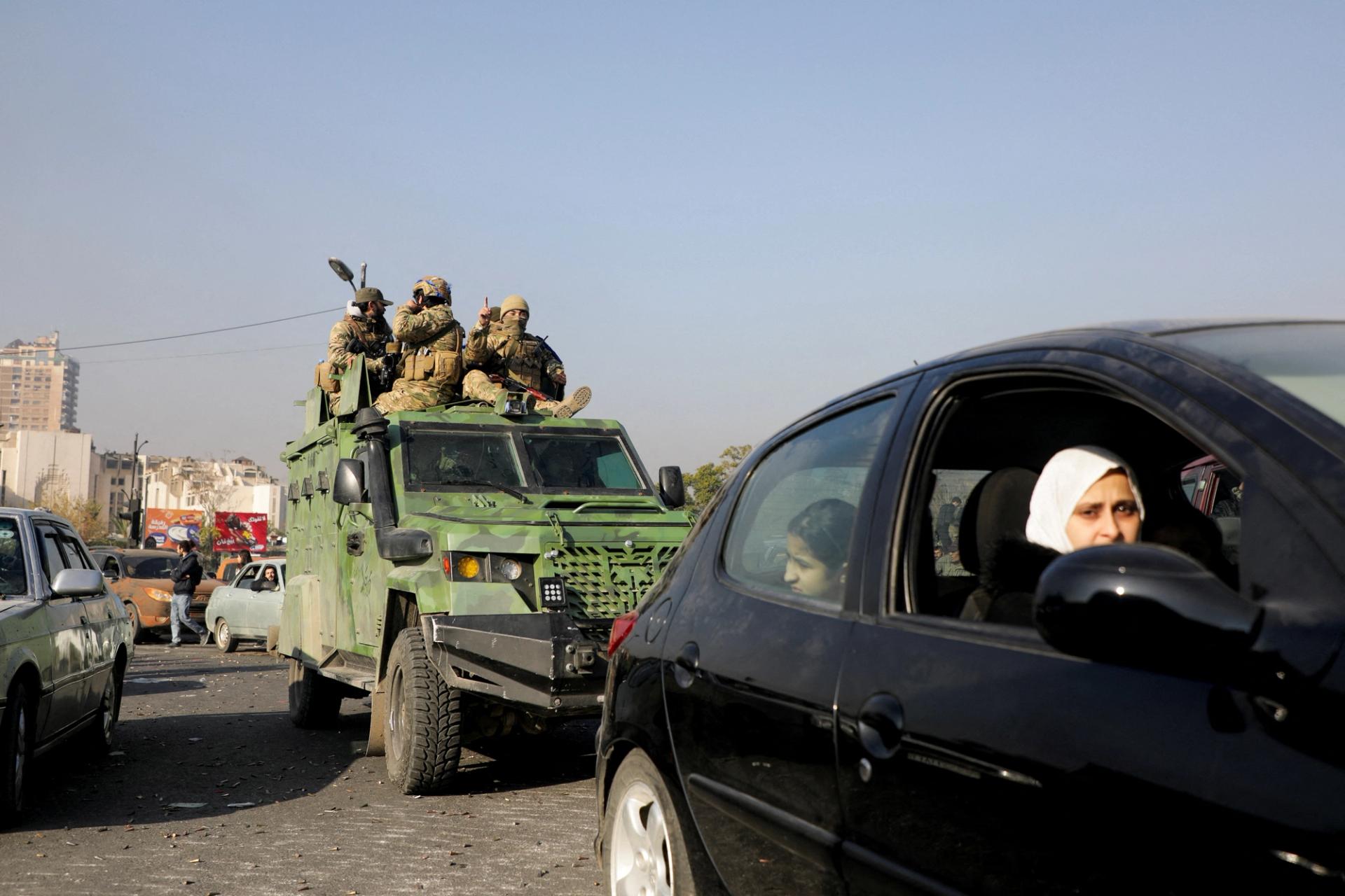 Rebel fighters ride a military vehicle, after they seized the capital