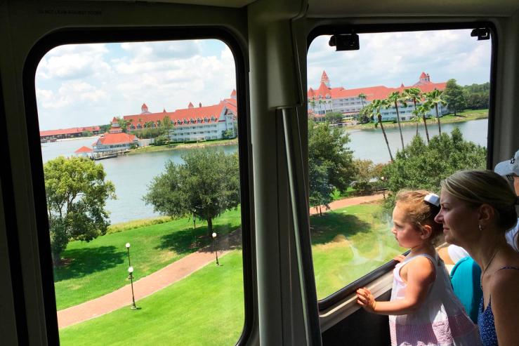 A mother and child look over the The Grand Floridian resort and Seven Seas Lagoon