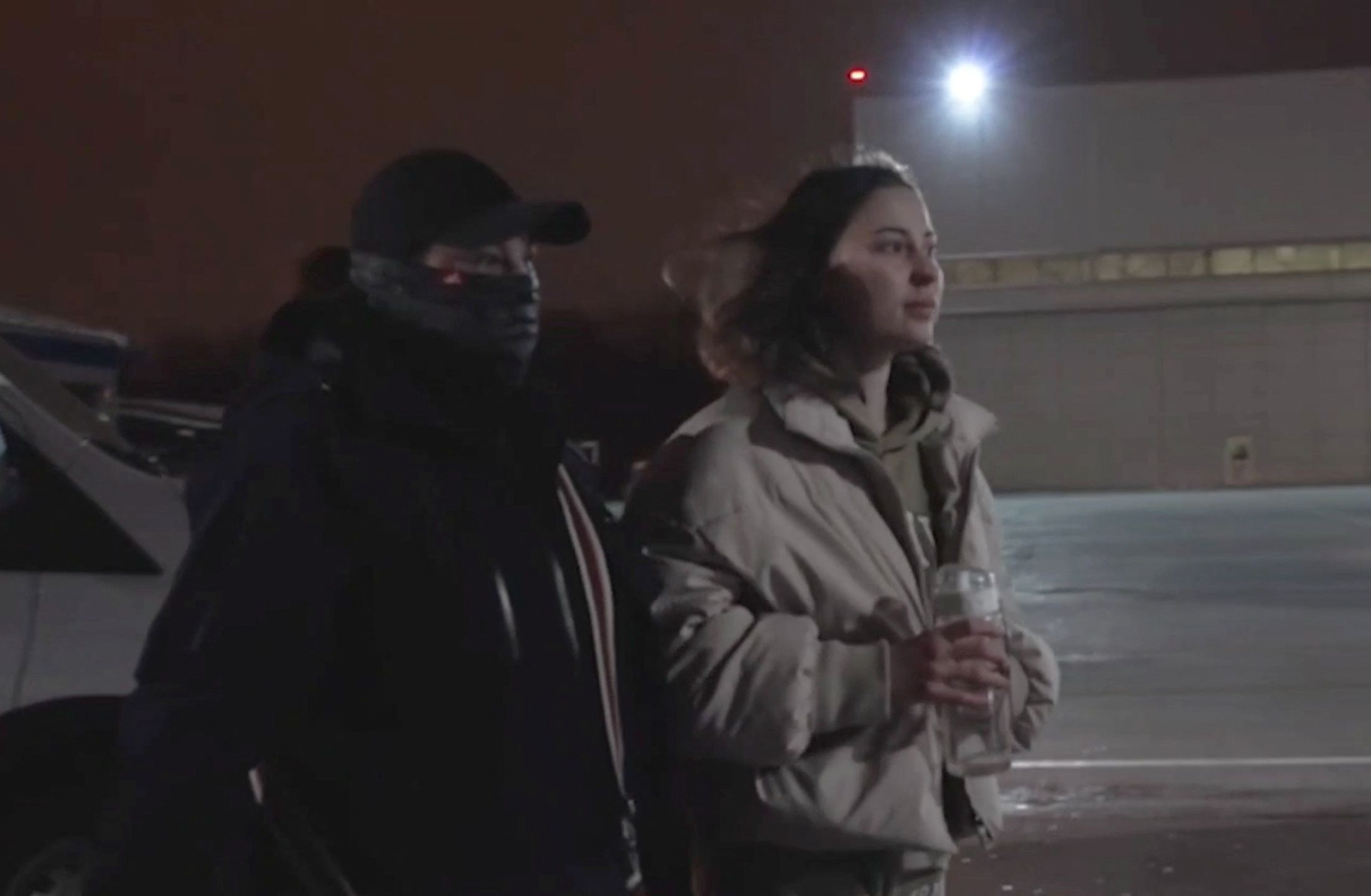 Russian-American citizen Ksenia Karelina, serving a 12-year prison sentence in Russia after she was found guilty of treason, is escorted by a security officer towards a plane at an airport in an unidentified location during a prisoner swap between Russia and the United States, in this still image from video broadcast in Russian state media April 10, 2025.
