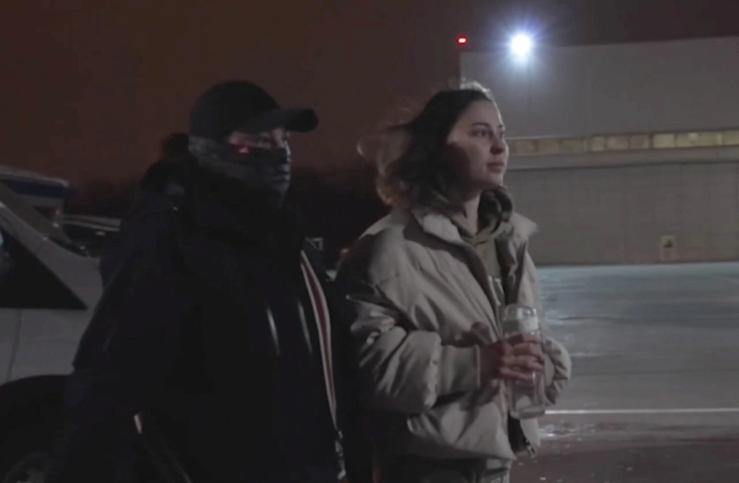 Russian-American citizen Ksenia Karelina, serving a 12-year prison sentence in Russia after she was found guilty of treason, is escorted by a security officer towards a plane at an airport in an unidentified location during a prisoner swap between Russia and the United States, in this still image from video broadcast in Russian state media April 10, 2025.