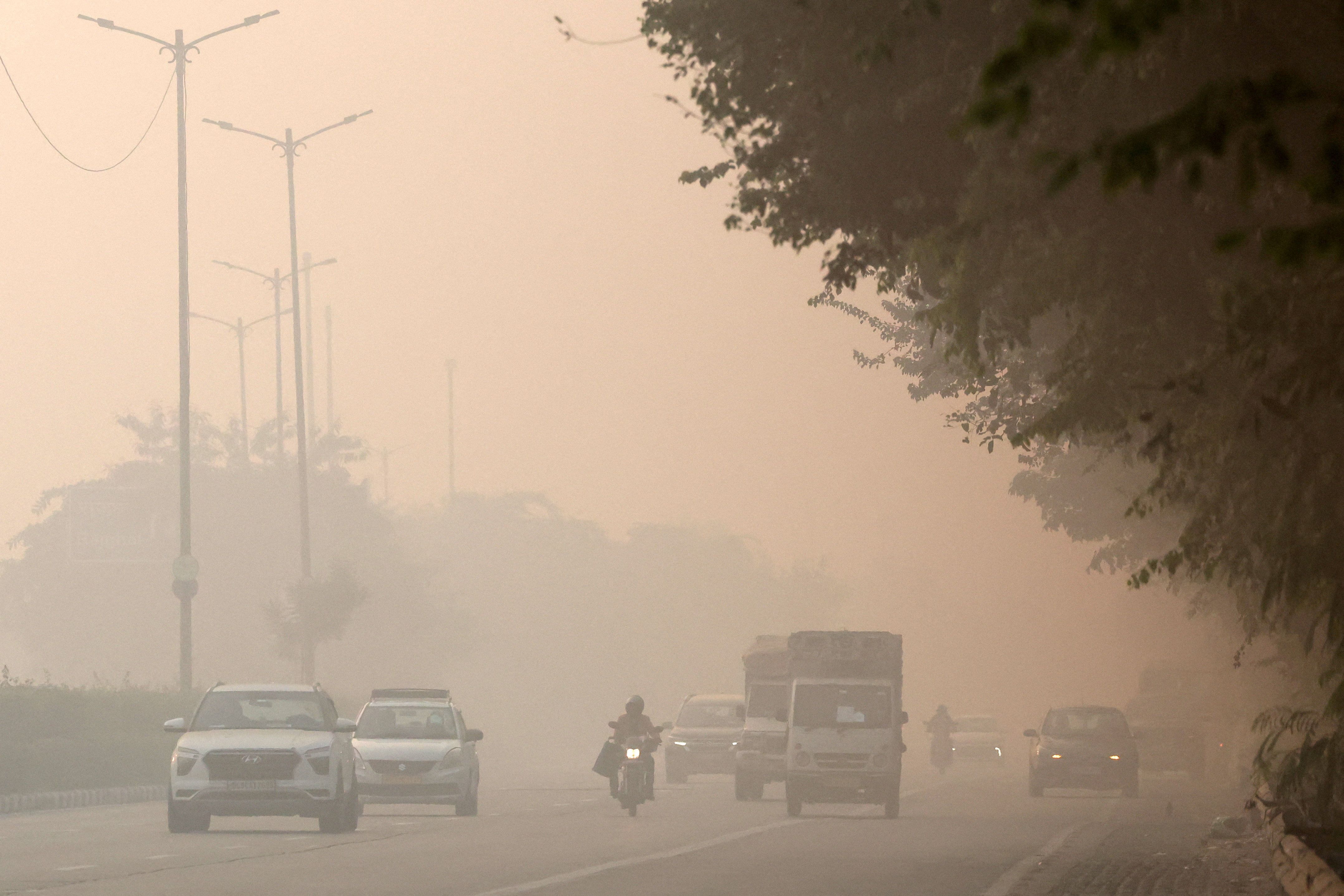 A newspaper vendor rides his bicycle on a smoggy morning in New Delhi