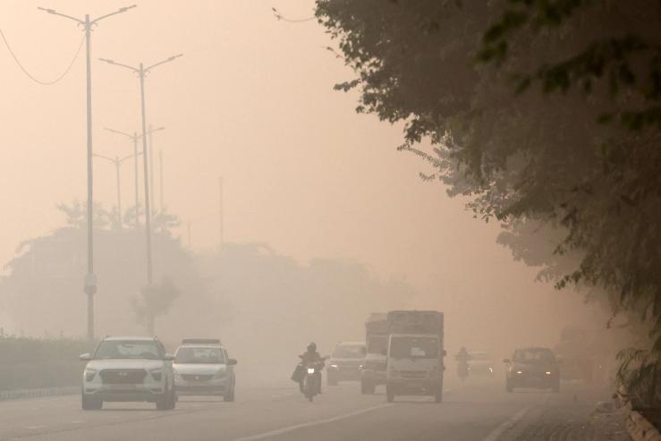 A newspaper vendor rides his bicycle on a smoggy morning in New Delhi