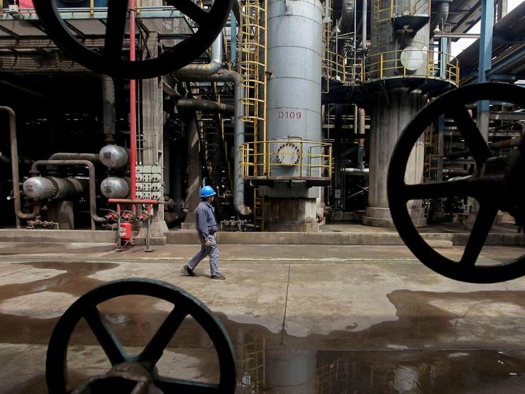 A worker walks past oil pipes at a refinery in Wuhan.