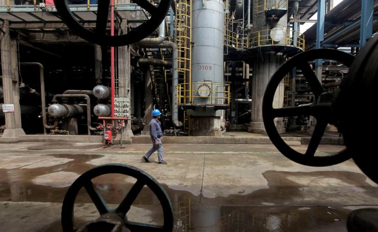 A worker walks past oil pipes at a refinery in Wuhan.