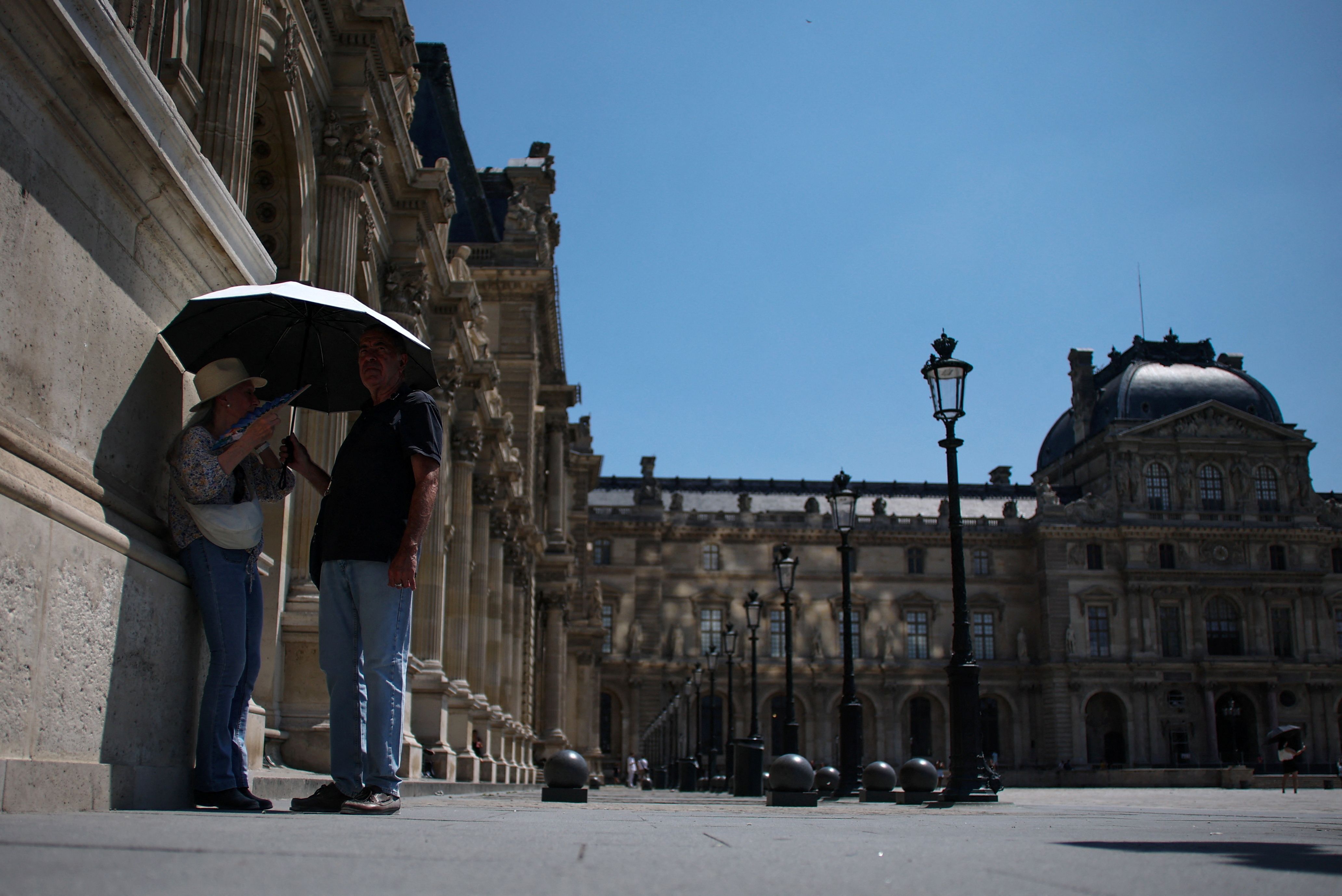 People holding an umbrella to protect themselves form the sun in Paris.