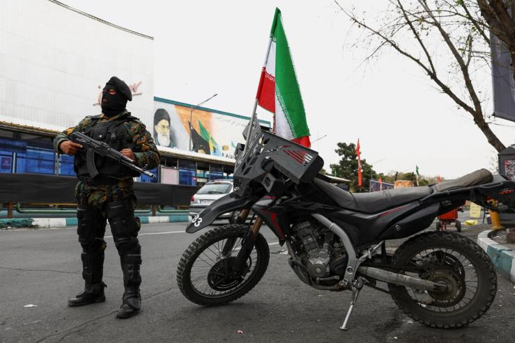 A member of a police force stands guard on a street, amid the U.S.-Israeli conflict with Iran, in Tehran