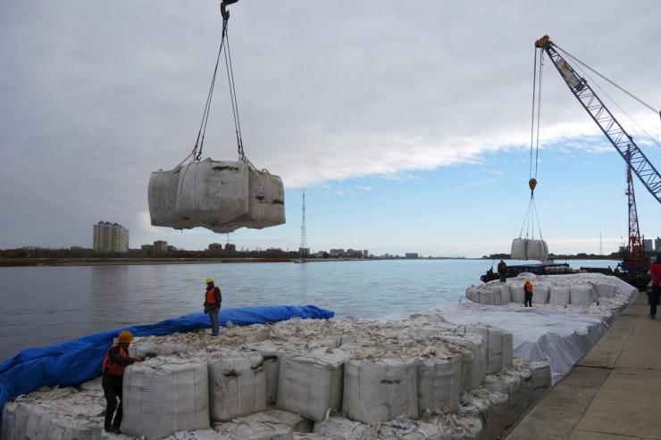 Workers stand near a crane unloading sacks of imported soybeans from Russia at Heihe port in Heilongjiang province, China October 10, 2018.