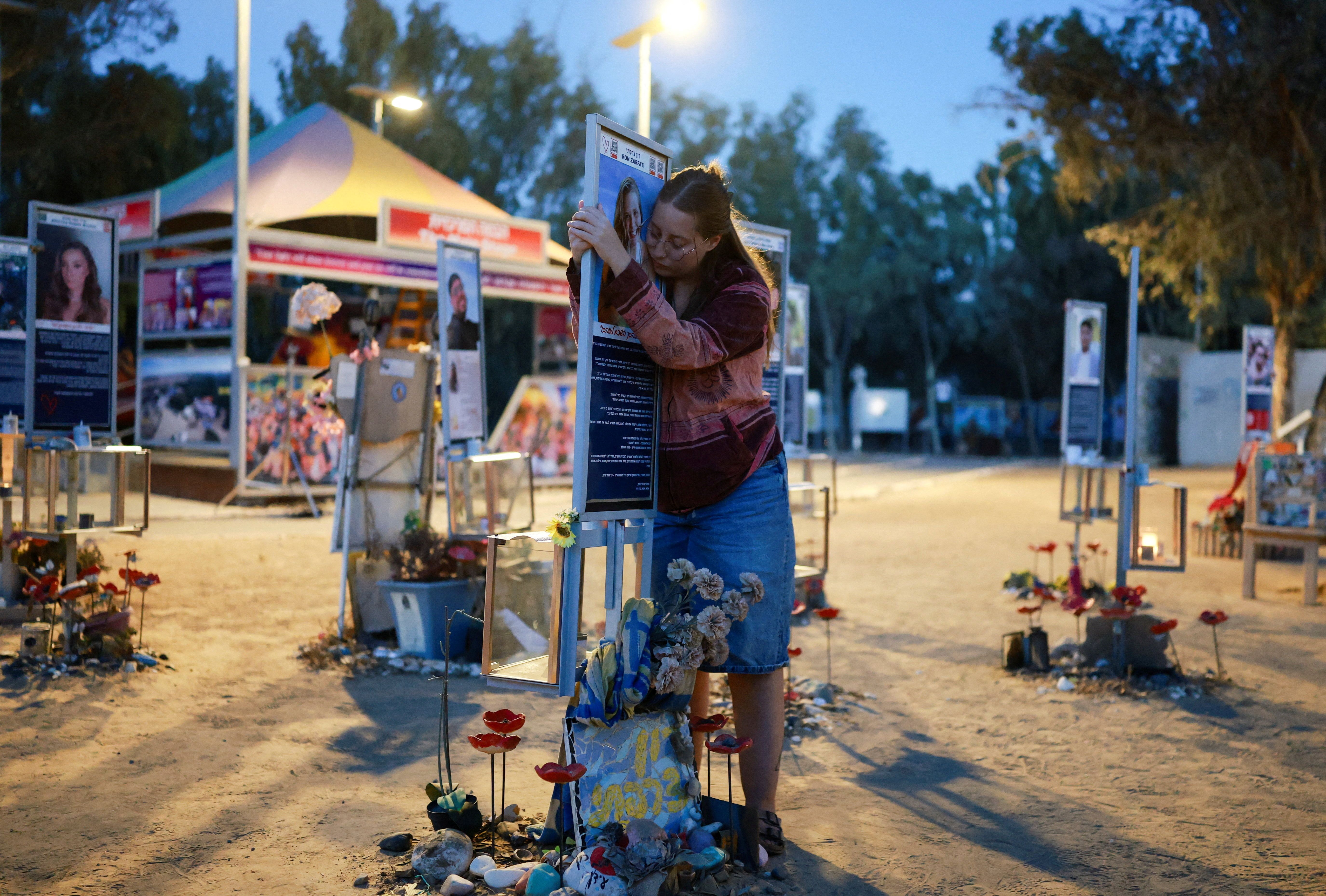 A woman hugs a sign at a memorial at the site of the Nova music festival